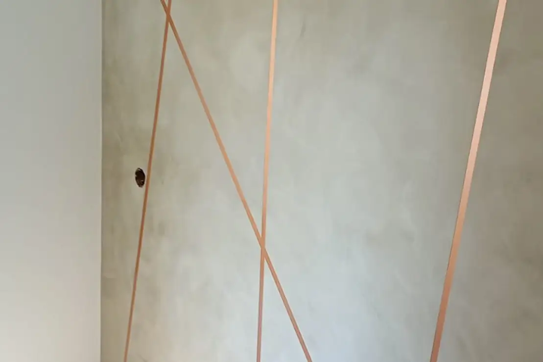Parede decorativa em cimento queimado com fitas de cobre